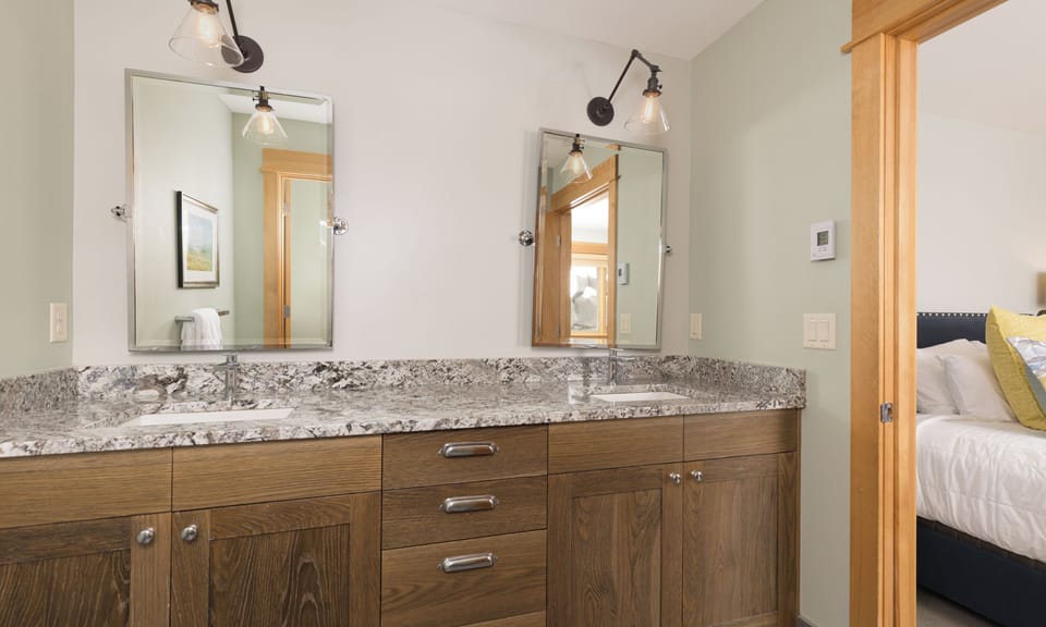 Step into your beautifully appointed ensuite bathroom with dual vanities and elegant granite countertops, perfect for your morning routine.