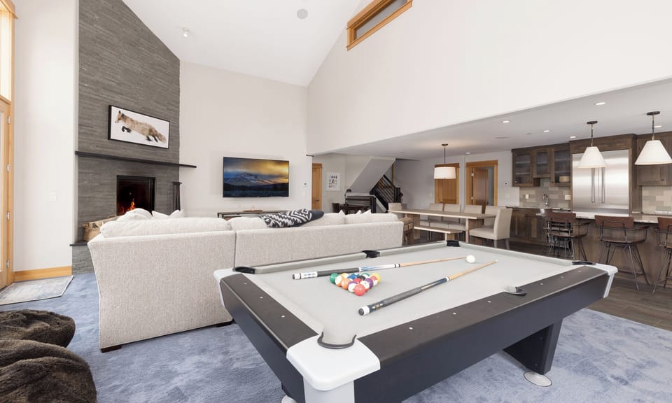 Unwind in your open-concept living space with a crackling fireplace, modern pool table, and gourmet kitchen perfect for entertaining.