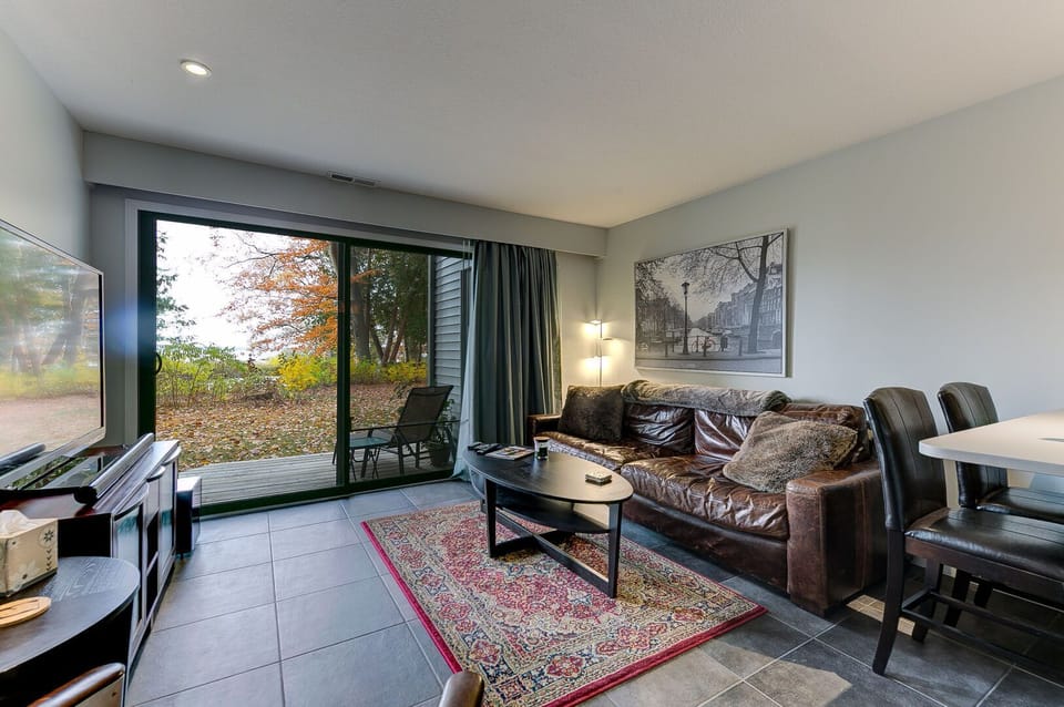 The unit features a luxurious leather couch, an attached balcony, and a impressive 65" smart TV for a comfortable and entertaining living space.