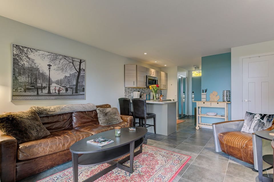 The unit is adorned with a stylish leather couch, a charming breakfast nook, and a kitchen equipped with a microwave for added convenience.