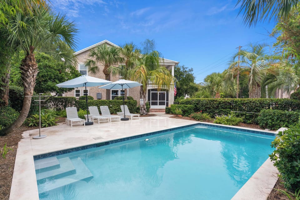 The property sits nestled among lush palms and tropical greenery, with a private pool awaiting your arrival under sunny Florida skies.