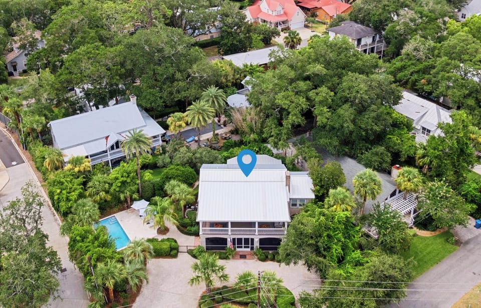 Aerial view of the property nestled in a lush, tree-lined neighborhood with a private pool and tropical landscaping.