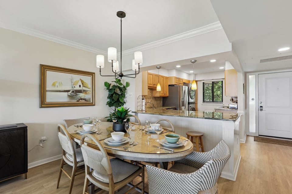 Your open-concept dining and kitchen area invites you to gather around a welcoming table set for leisurely meals. Bright pendant lights and warm wood tones create a cozy atmosphere where you can cook, dine, and relax all in one seamless space.