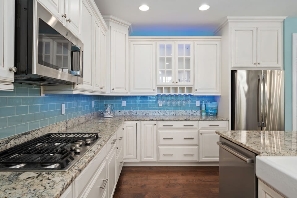Kitchen with under counter lighting & hanging wine glasses.