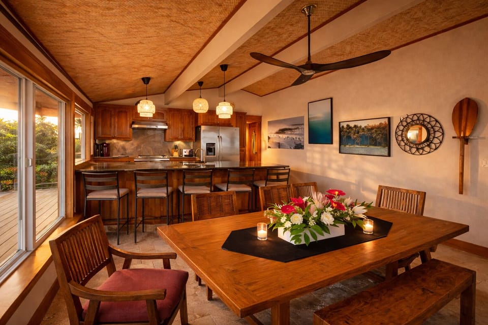 Warm wood dining for eight with soft light and relaxed island feel.