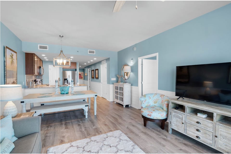 Unwind in your spacious living area with soothing blue walls, modern kitchen, and coastal-themed furnishings that create the perfect retreat.