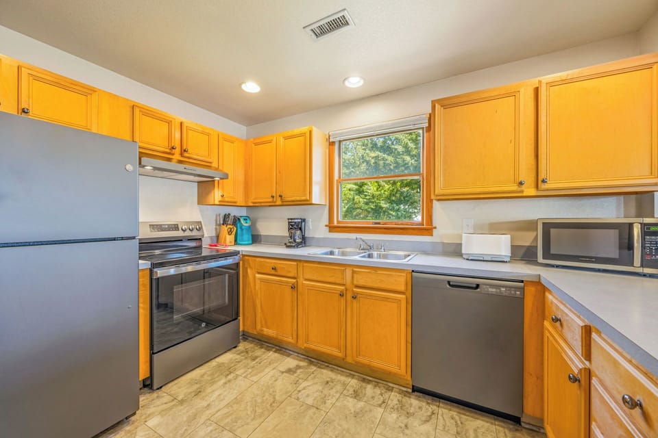 Your bright, fully-equipped kitchen invites effortless meal prep with stainless appliances, ample counter space, and warm natural light streaming through the window.