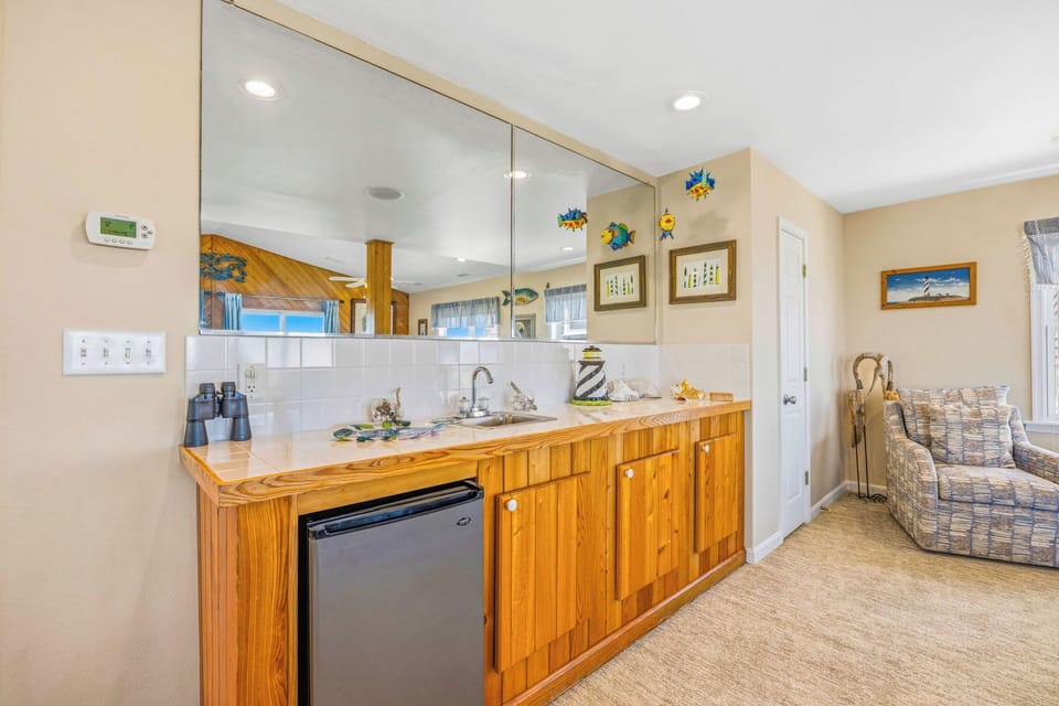 This charming coastal kitchenette features warm wood cabinetry, a convenient mini-fridge, and cheerful beach-themed décor—perfect for refreshing between seaside adventures and lazy afternoon lounging.