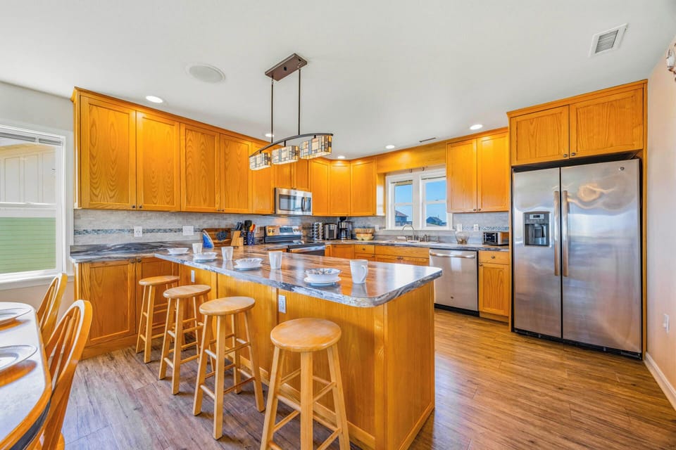 This bright, fully equipped kitchen invites you to whip up delicious meals with modern appliances, ample counter space, and a welcoming island for gathering with loved ones over coffee.