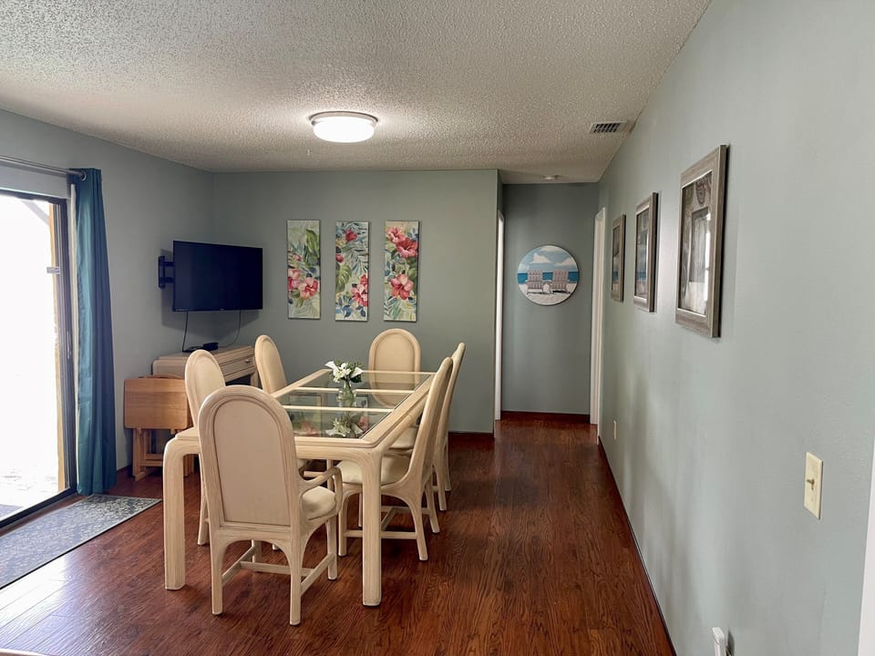 Dining room with plenty of seating and tv, sliding door opens to screened pool.