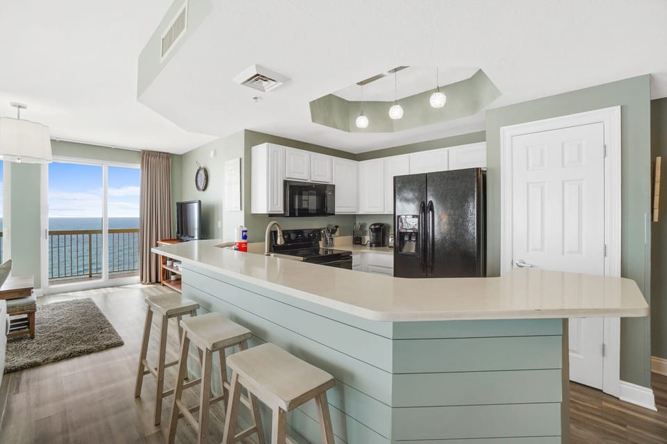 Your bright oceanfront kitchen awaits with modern appliances and a breakfast bar perfect for morning coffee with stunning sea views.