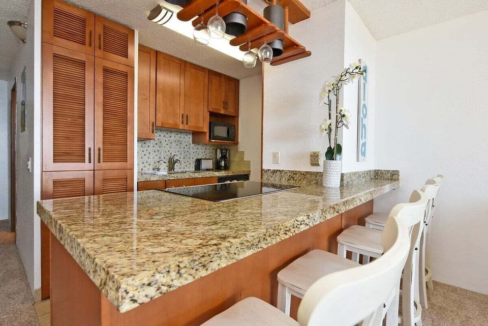 Well equipped kitchen with granite countertop, stainless steel appliances and wooden cabinetry