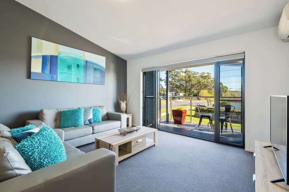 Huskisson holiday accommodation lounge room with small north facing deck at Nautilus Jervis Bay. Lounge includes a Smart TV and Air Con.