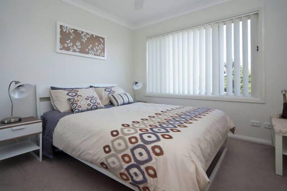 Comfortable queen bed with large picture windows and ceiling fan