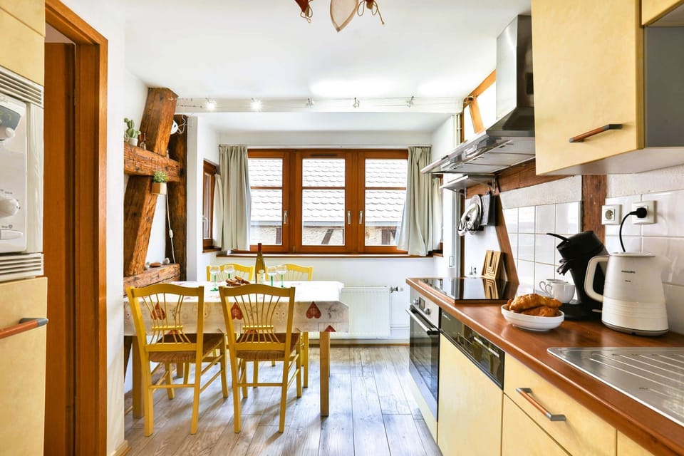 Espace de vie en longueur avec cuisine équipée avec lave-vaisselle et table à manger avec 4 chaises