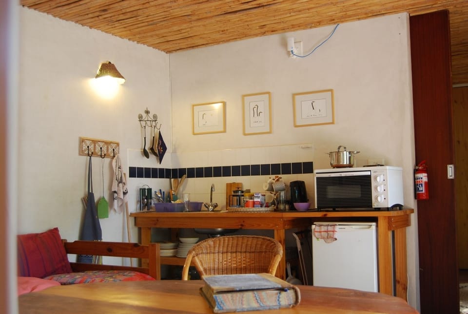 A kitchenette with a fridge, oven & 2 hot plates, kettle, knives, forks etc