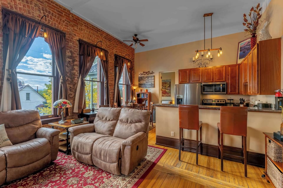 【Living Room】 14ft ceilings and exposed brick — the 1880s architecture does the decorating