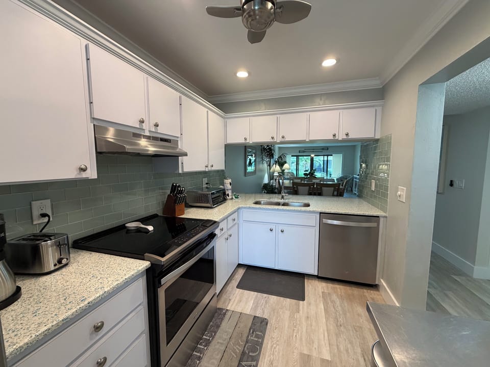 Your modern kitchen features gleaming appliances, granite countertops, and crisp white cabinetry - perfect for preparing meals during your stay.
