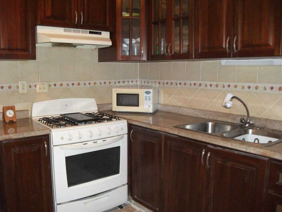kitchen has stove, microwave, refrigerator, dishware, toaster, cabinets