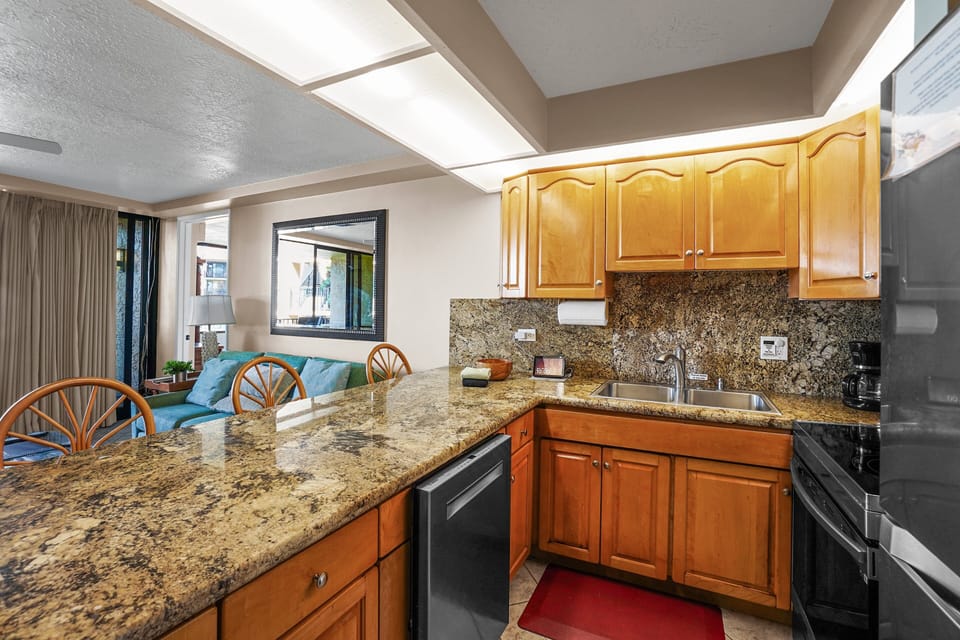 Enjoy a fully equipped open-concept kitchen with sleek granite countertops, modern appliances, and custom wood cabinetry—perfect for cooking meals in your beachside retreat.
