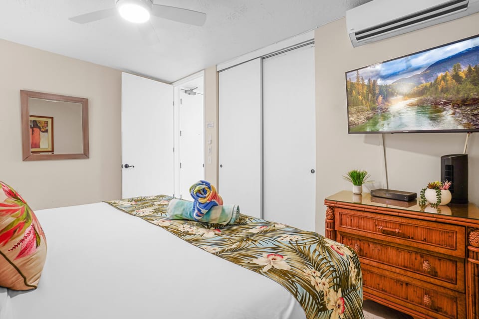 This bright and cozy bedroom features a smart TV, spacious closet, and stylish decor, providing a relaxing environment for your Maui getaway.'