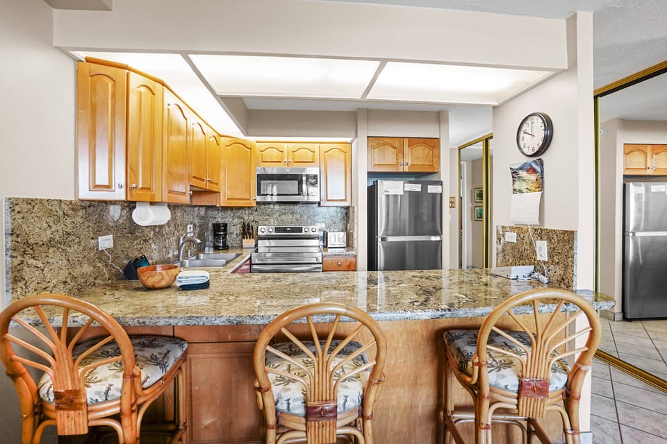 This bright kitchen boasts tropical-inspired décor, a bar counter, and high-end finishes—offering a comfortable and stylish setting for vacation dining.