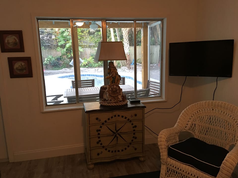 Den highlighting view of back porch and swimming pool