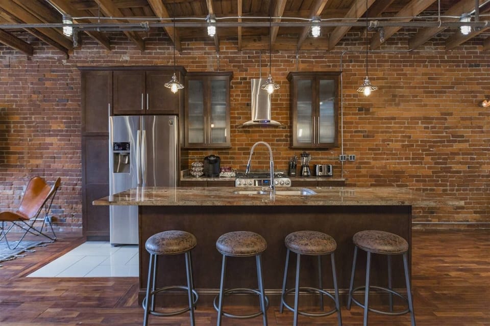 - Spacious kitchen with stainless appliances and island seating   - Brick walls and warm finishes enhance the industrial look   - Fully equipped cooking space for extended stays