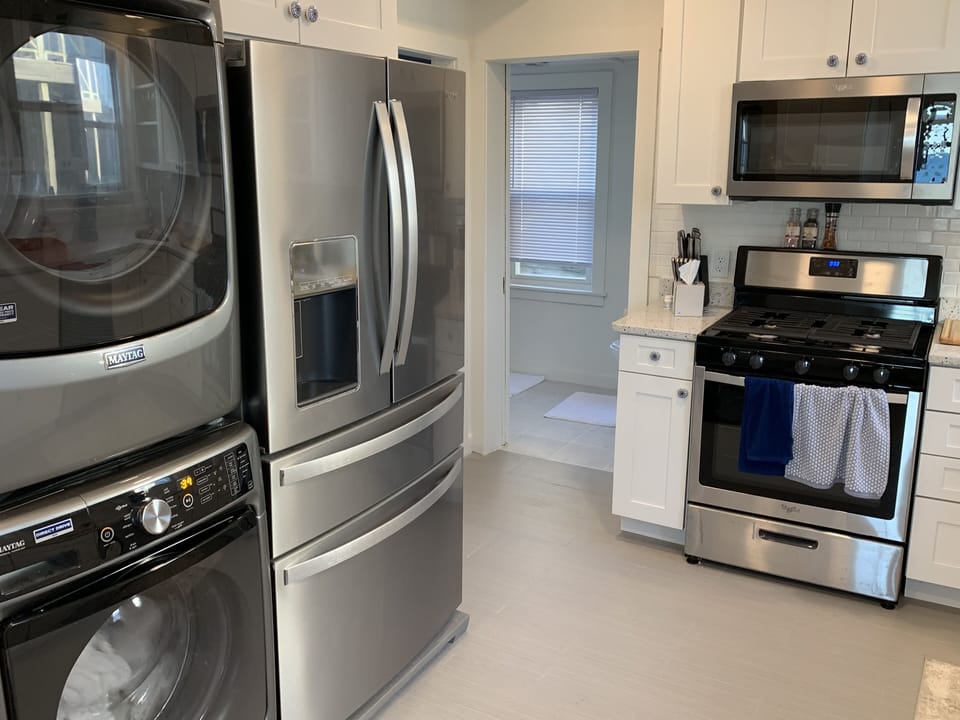Kitchen with a view of the washer, dryer, fridge, gas stove and microwave
