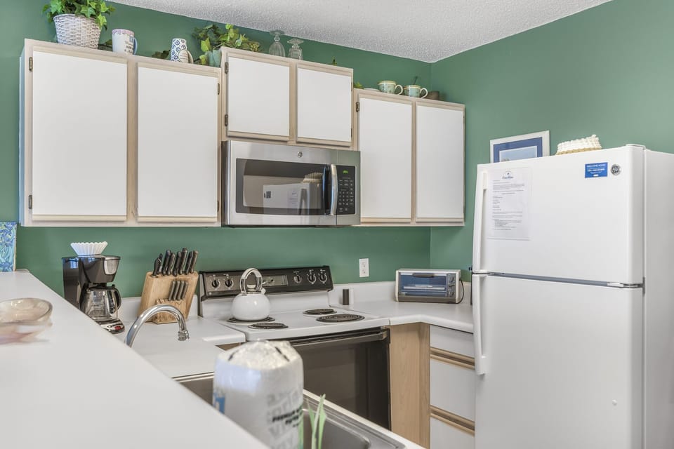 A bright kitchen with full appliances for cooking in.
