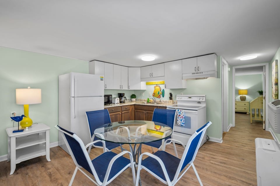 Your bright, open kitchen flows seamlessly into the dining area, where you'll enjoy meals at the cheerful glass table surrounded by coastal blue chairs.