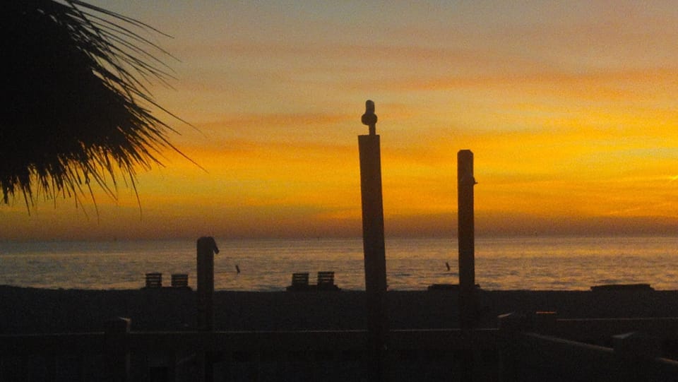 Sunset, over the beach, viewed from the pool area. Actual photo I took.