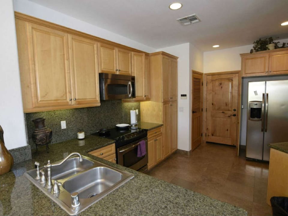 The gourmet kitchen at Condo 21-4 includes a large stainless steel refrigerator with a built-in water and ice dispenser—perfect for keeping drinks cold and groceries fresh during your stay