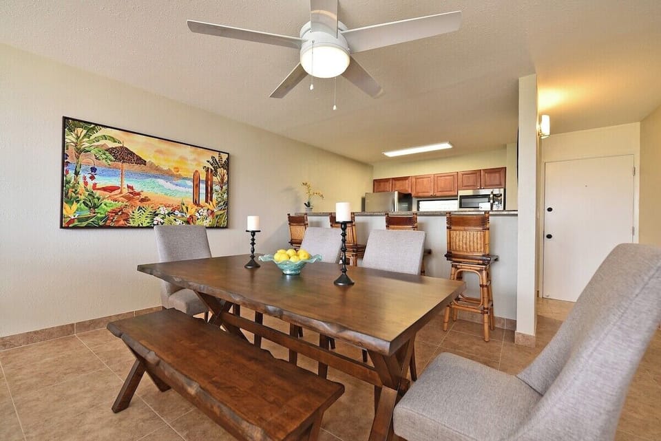 Dining area with wooden table, bench seating, and colorful artwork.