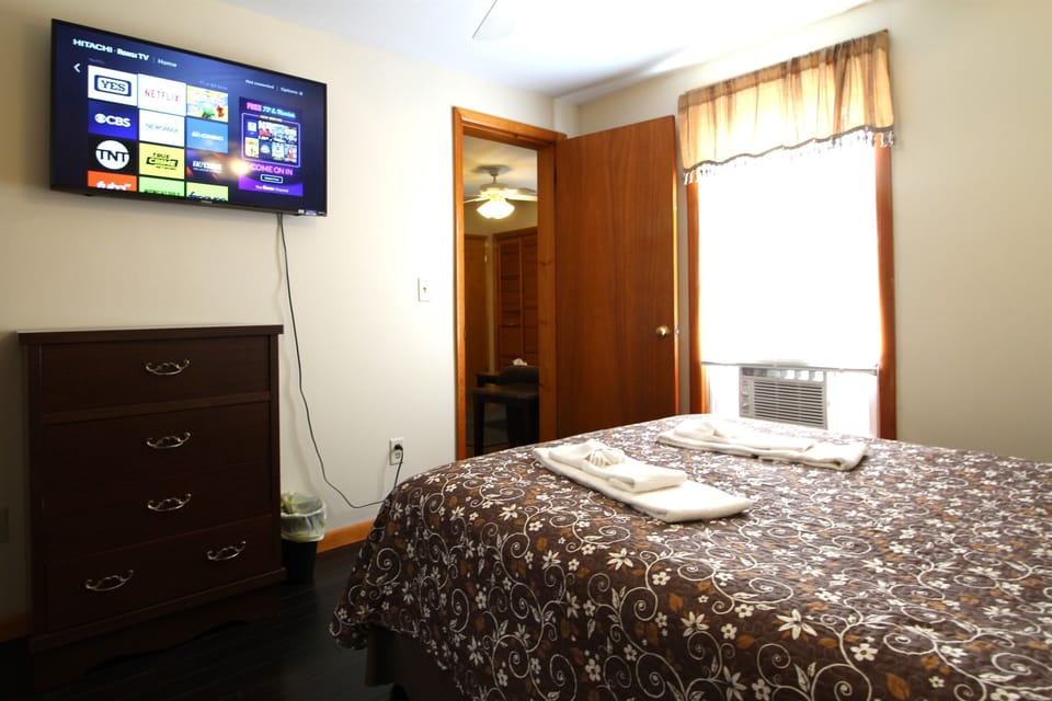 The cozy bedroom features a wall mounted flat screen smart Roku TV for relaxing after a long day at the ballpark or sightseeing