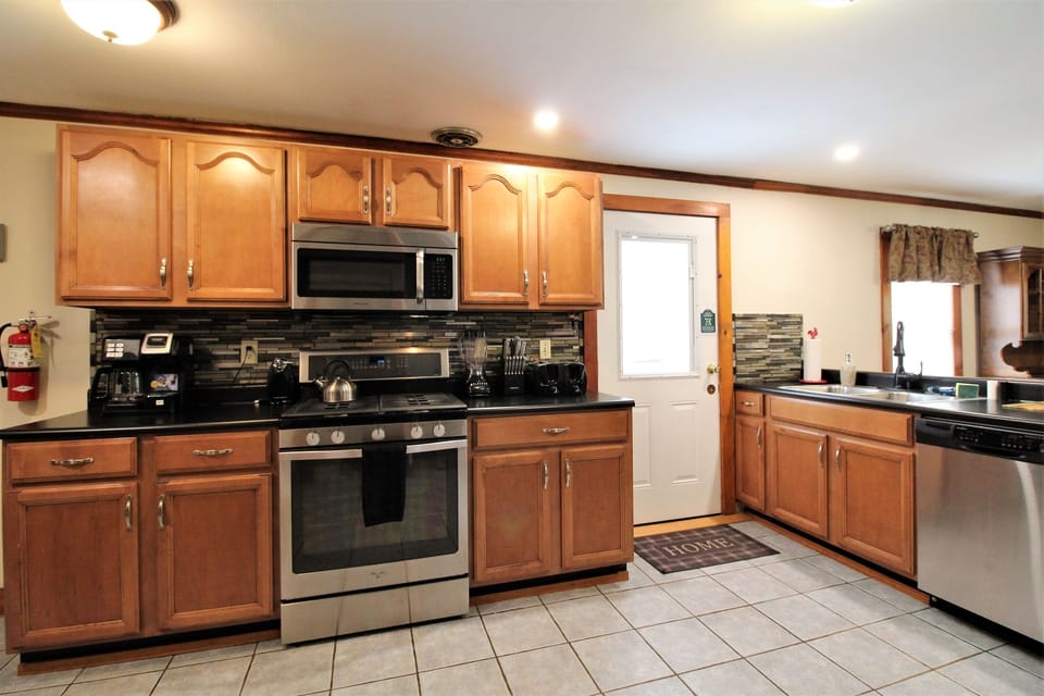 Spacious kitchen with modern tiled backsplash; stainless steel appliances and easy access to deck.