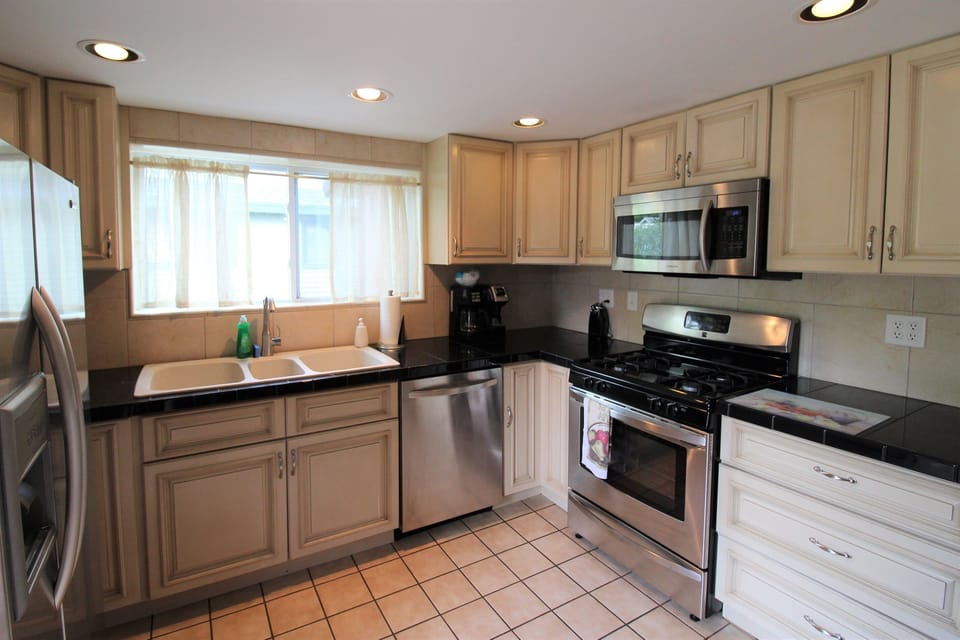 Modern, spacious kitchen with triple basin sink and stainless steel appliances