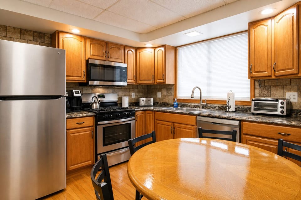 Fully equipped kitchen with hardwood floors and tiled backsplash.  Features a gas range, microwave, dishwasher, and full size refrigerator with automatic ice maker.