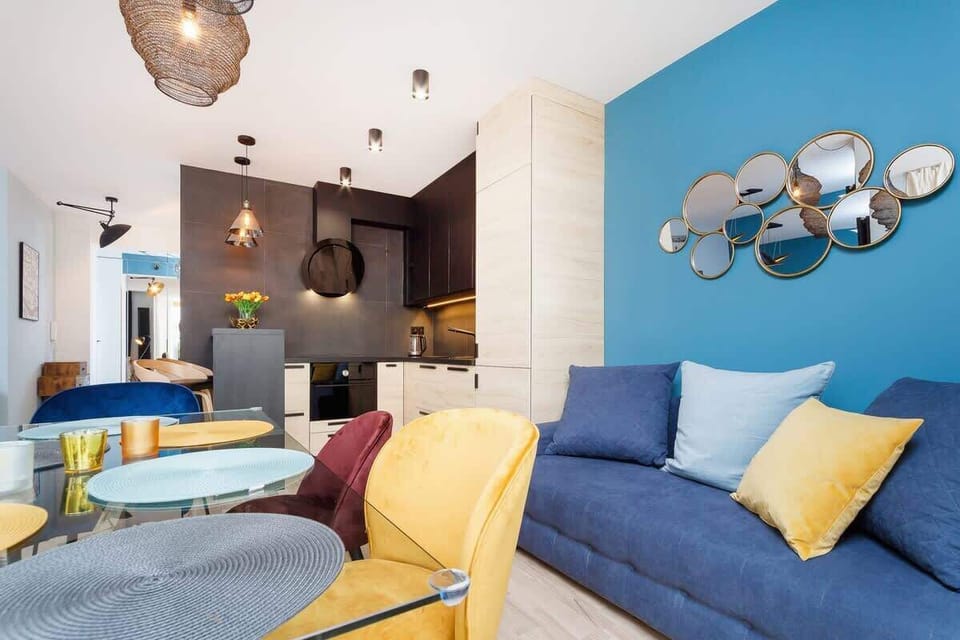 A stylish room with a black and blue color scheme, featuring a dark dining table, blue curtains, and a cozy seating area with decorative lighting.