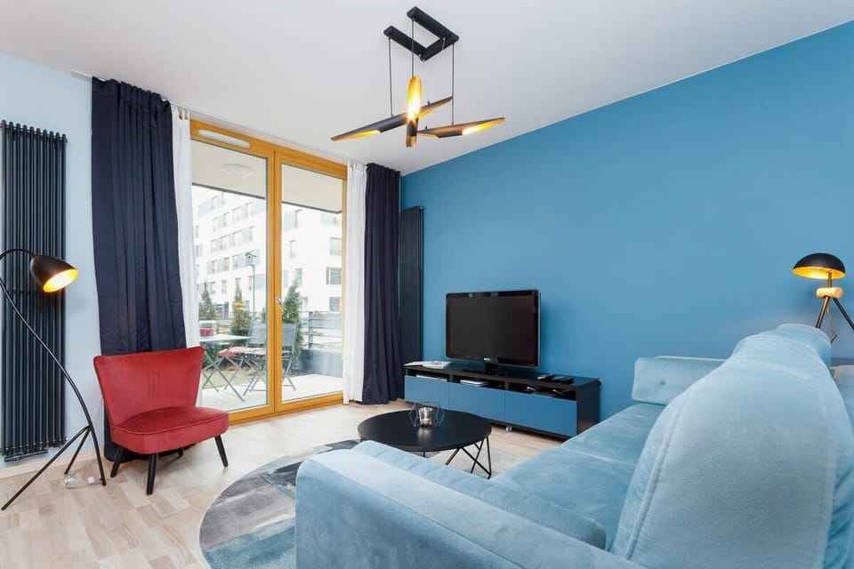 A cozy living room with blue walls and a large blue sofa, complemented by a modern coffee table and colorful artwork on the wall.