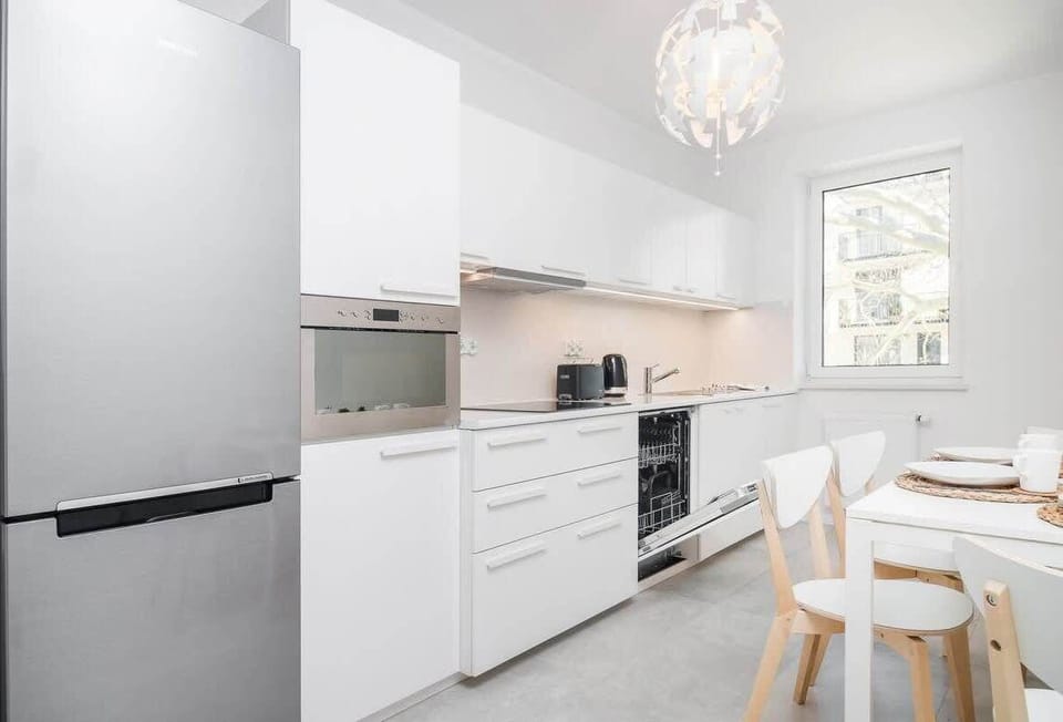 Modern kitchen of with dining area, dishwasher, oven, kettle, coffee machine and sink