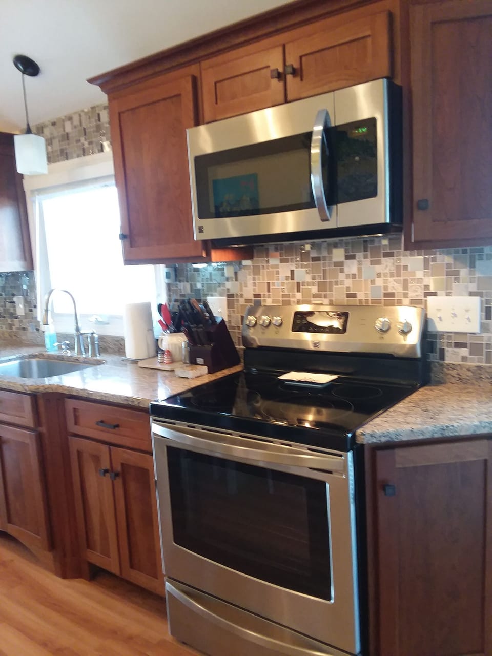 Stove with microwave, granite countertops, tiled backsplash