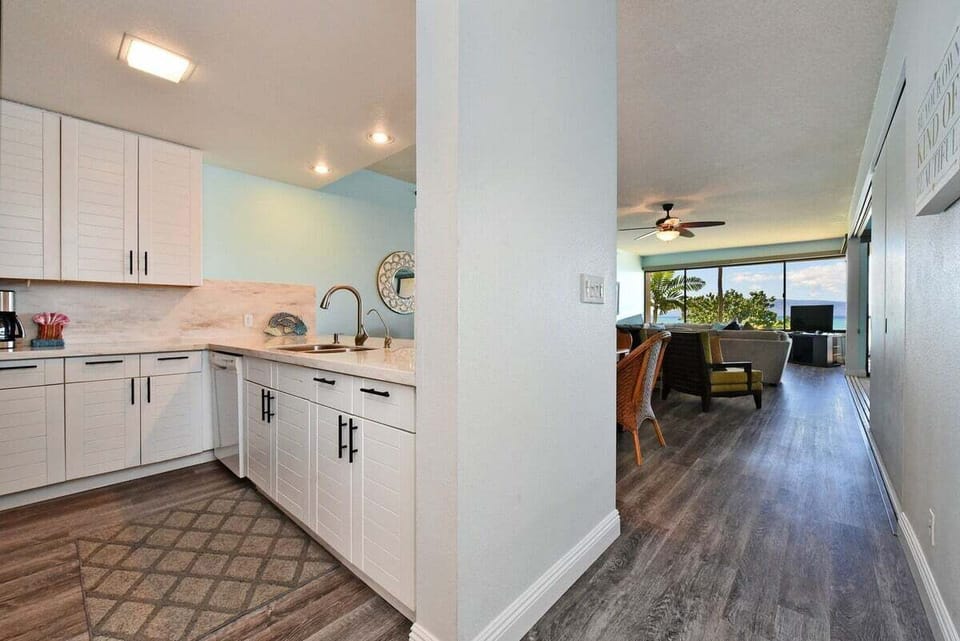 Corner kitchen view with marble counters and patterned floor, dining and living areas stretching into the distance.