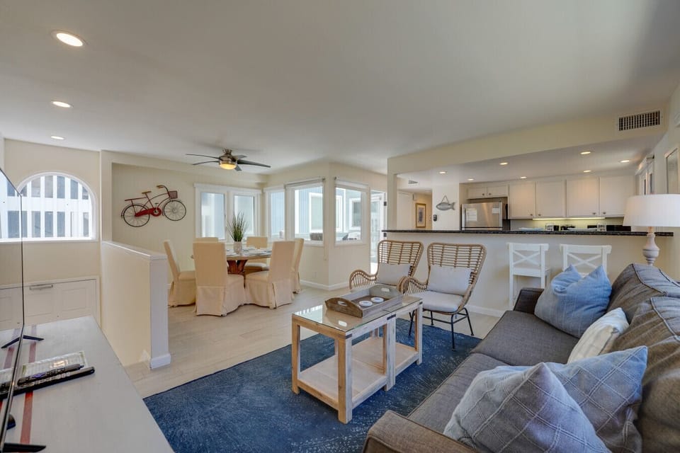 Bright and airy open-concept layout featuring a spacious living room, stylish wicker seating, bar seating at the granite breakfast counter, and a dining area with seating for six.