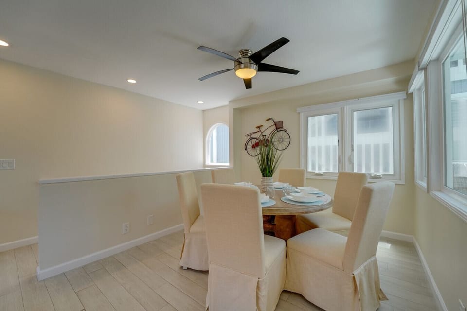 Bright and airy open-concept layout featuring a spacious living room, stylish wicker seating, bar seating at the granite breakfast counter, and a dining area with seating for six.