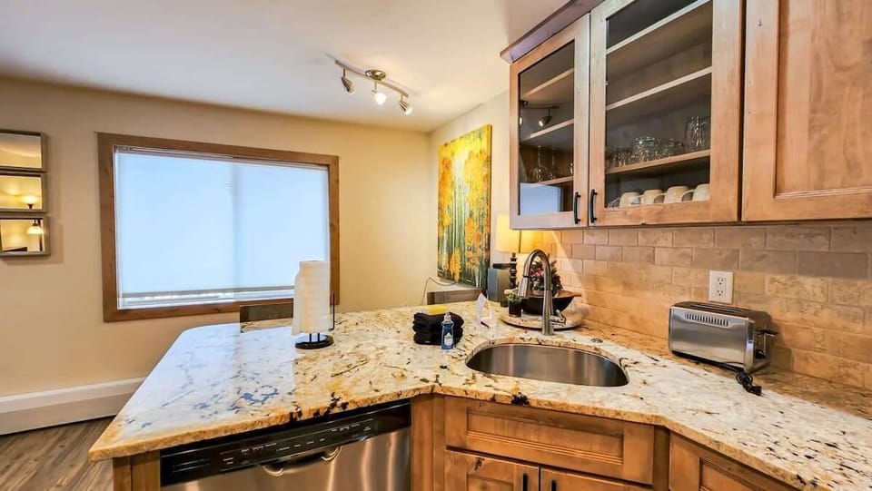 The fabulous, remodeled kitchen features stainless steel appliances, a tile backsplash and modern finishes. It also has a bar that makes for easy serving and dining for two.