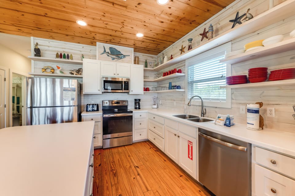 Cook with ease in this coastal-inspired kitchen featuring nautical décor, stainless steel appliances, and warm wood accents.