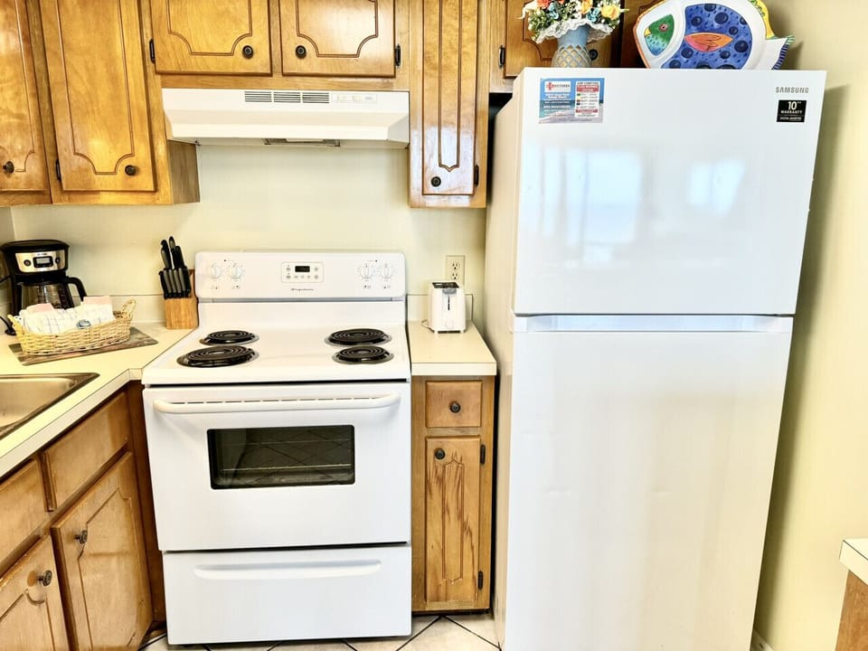 Kitchen with fridge and electric stove/oven unit. Features 4 burners on top.
