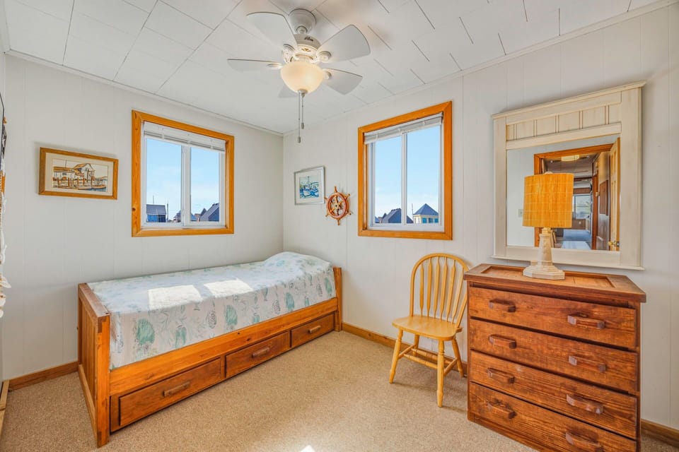 Your cozy bedroom features charming nautical touches, warm wood furnishings, and peaceful natural light from dual windows.