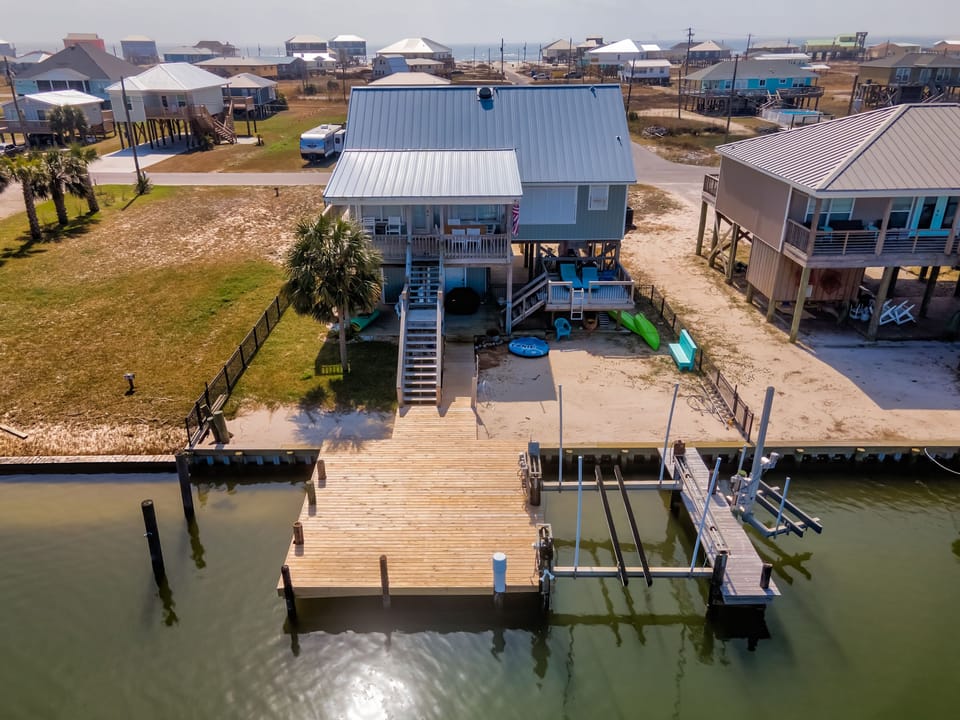 Waterfront beach house with private dock, kayaks, and boat lift positioned on scenic canal in coastal community.